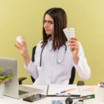 A doctor holding blister packs of vitamins, expressing curiosity, illustrating the question: How long does it take for vitamins to work?