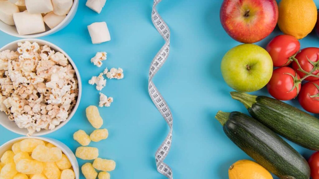 Variety of healthy and unhealthy foods with measuring tape on blue background illustrating ganglion cyst vitamin deficiency