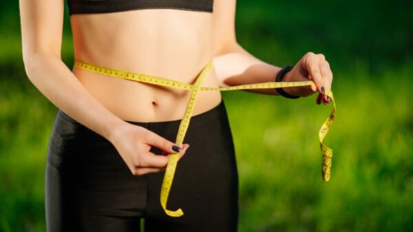 Person measuring waist to track progress in the stages of noticing weight loss