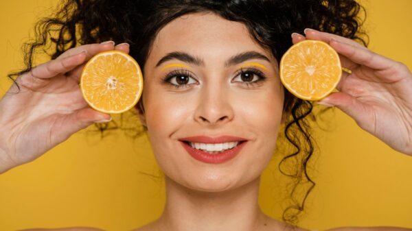 Woman holding orange slices to her face, representing Vitamin C Serum Before and After effects on skin.