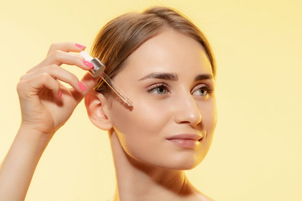 Woman applying Vitamin C serum to her face, illustrating the benefits of vitamin c serum before and after.