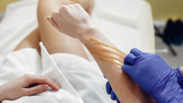 Person receiving a waxing treatment on their arm and revealing the truth Does Waxing Reduce Hair Growth?