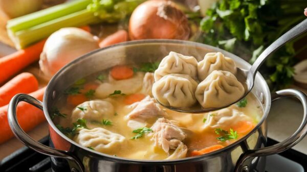 Chicken Dumpling Soup A Pot Of Homemade Chicken Dumpling Soup On The Stove, Filled With Tender Chicken Pieces, Sliced Carrots, And Fluffy Dumplings. A Ladle Is Lifting Three Perfectly Cooked Dumplings From The Soup, With Fresh Ingredients Like Celery, Onions, And Parsley Visible In The Background.