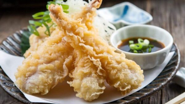 A Plate Of Crispy Chicken Tempura Served With A Side Of Dipping Sauce Garnished With Green Onions.