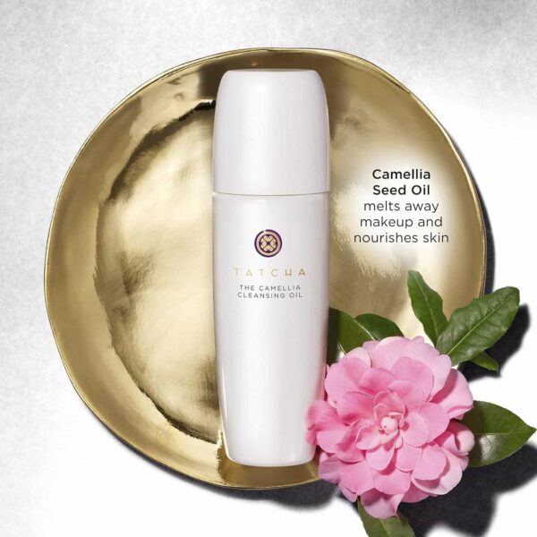 Tatcha Camellia Cleansing Oil Bottle On A Golden Plate With Camellia Flowers And Leaves.