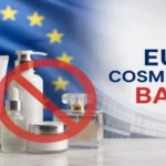 A Collection Of White Cosmetic Products Including A Tube, Pump Bottle, Dropper Serum, Cream Jar, And Perfume Bottle Overlaid With A Large Red Prohibition Symbol, Set Against A Waving European Union Flag Background — Visually Representing The Eu Ban On Restricted Cosmetic And Skincare Ingredients, With The Text &Quot;Eu Cosmetics Ban&Quot; Displayed In Bold Blue And Red Lettering On The Right.